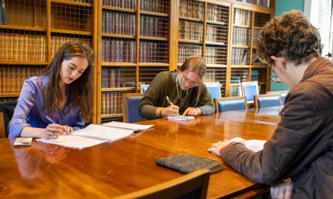 Three students studying at a table in a library