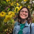 A picture of Nicola in front of some yellow flowers.